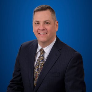 Mark Smigel headshot with blue background